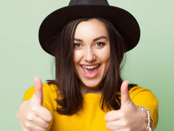 Girl with yellow jumper holding up her thumbs